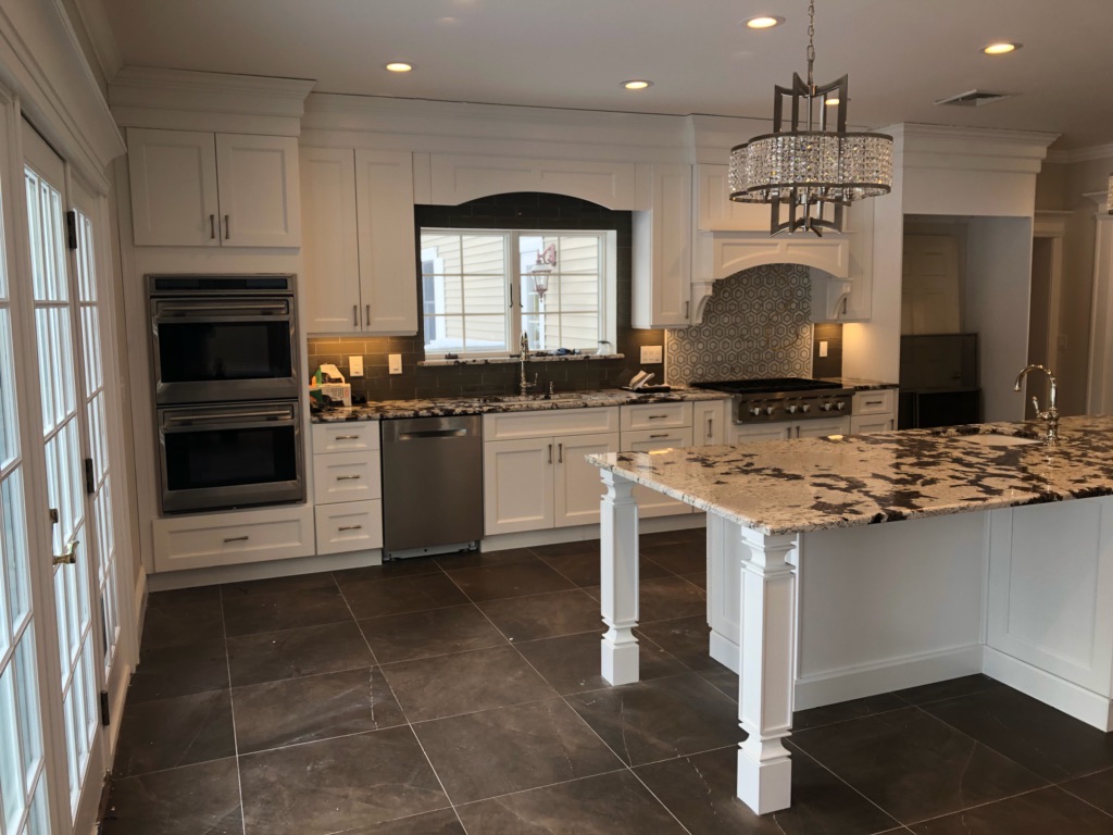 Finished kitchen with white shaker cabinets, granite island and double wall ovens