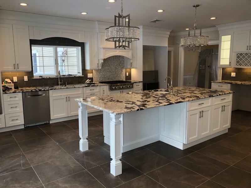 Kitchen island and range with subway tile backsplash and custom hood surround